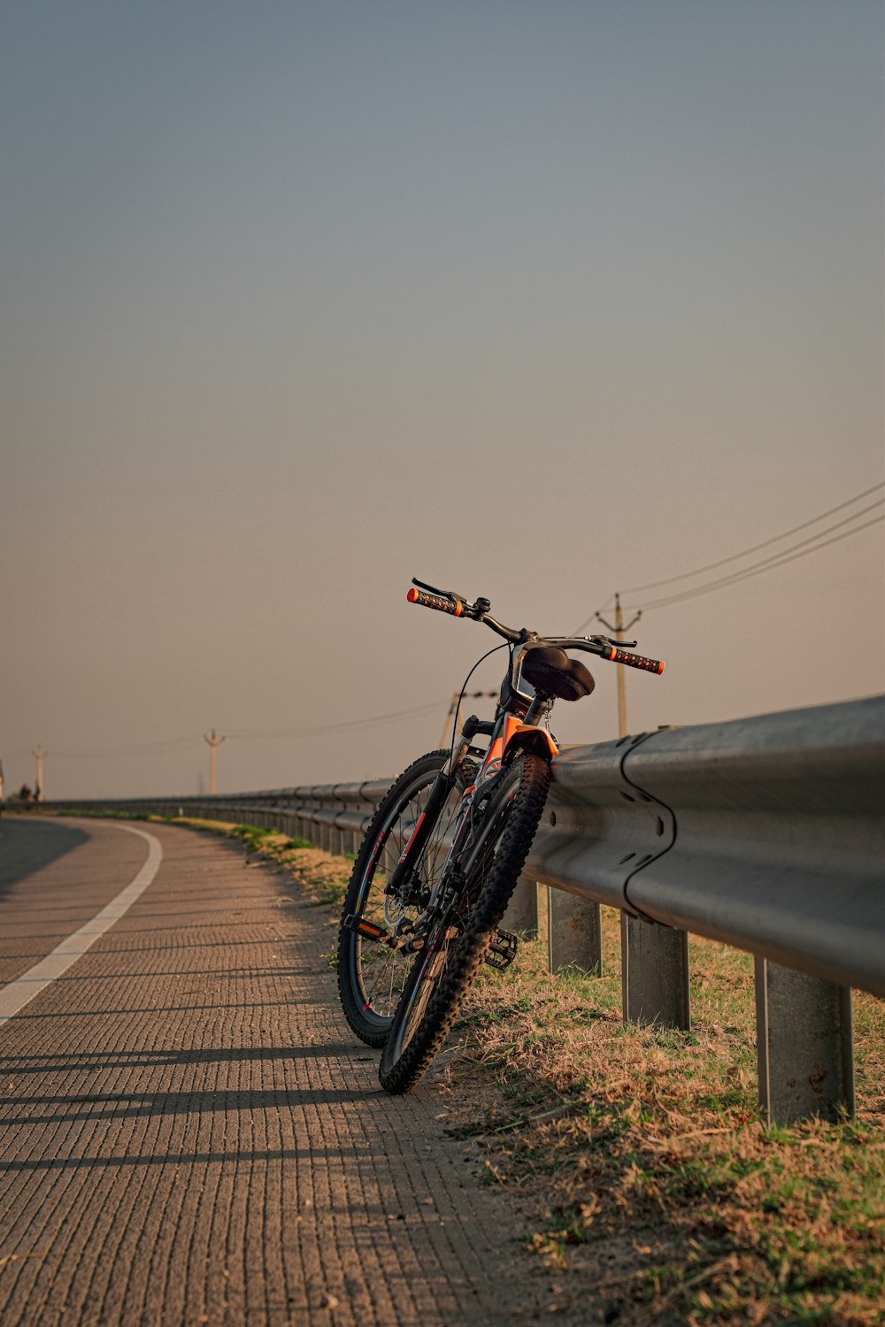 a bike leaning against a fence on the side of a road