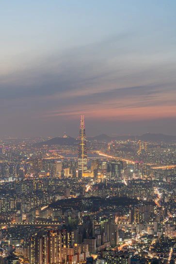 A sweeping vista of Ceikeinu’s five central cities under a twilight sky, each city distinct yet connected by glowing ley lines.