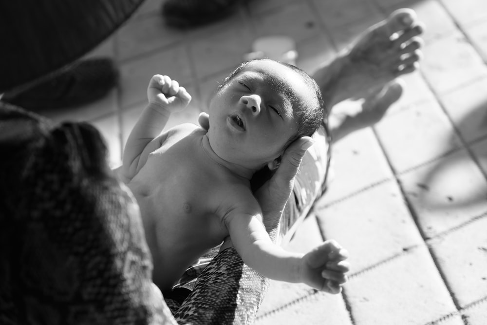 a black and white photo of a baby laying on the ground