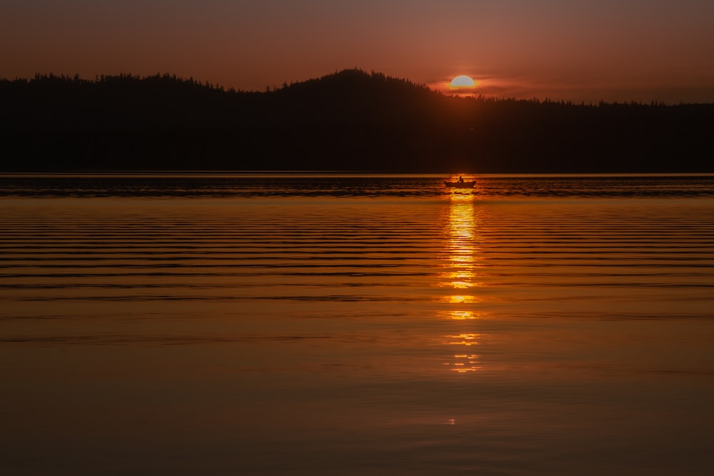 a large body of water with a sunset in the background