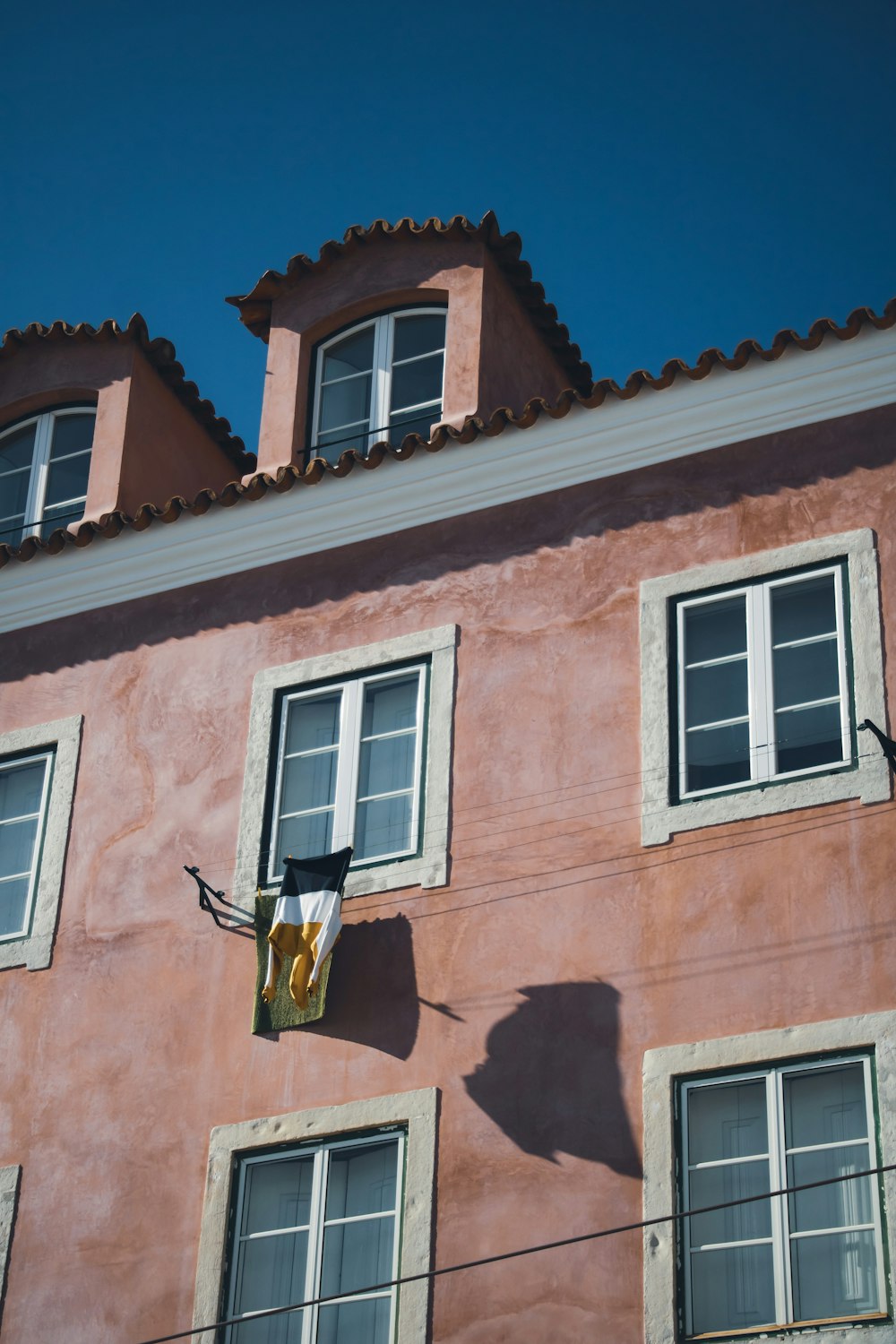 a pink building with three windows and a clock