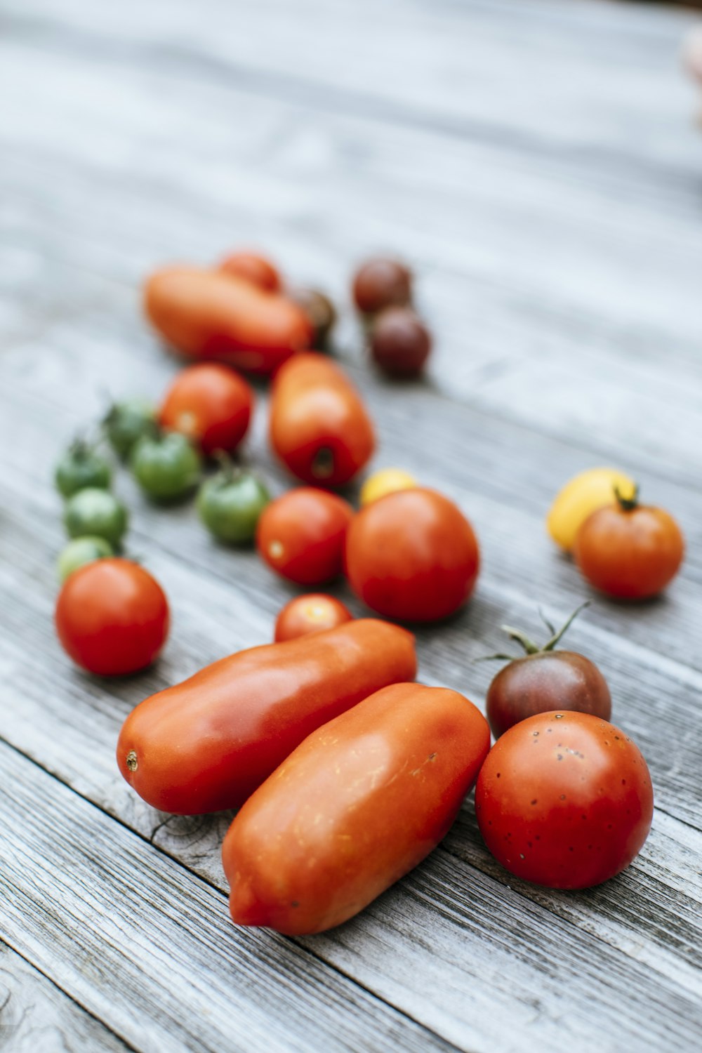 a group of tomatoes and other vegetables on a wooden table