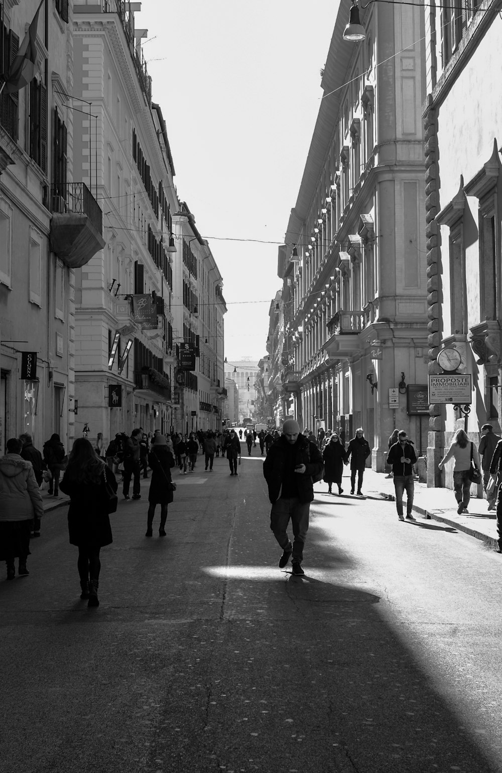 a group of people walking down a street next to tall buildings