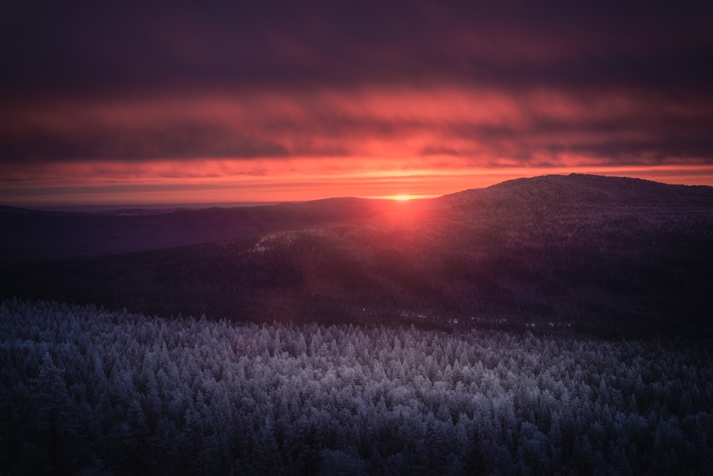 the sun is setting over a mountain range