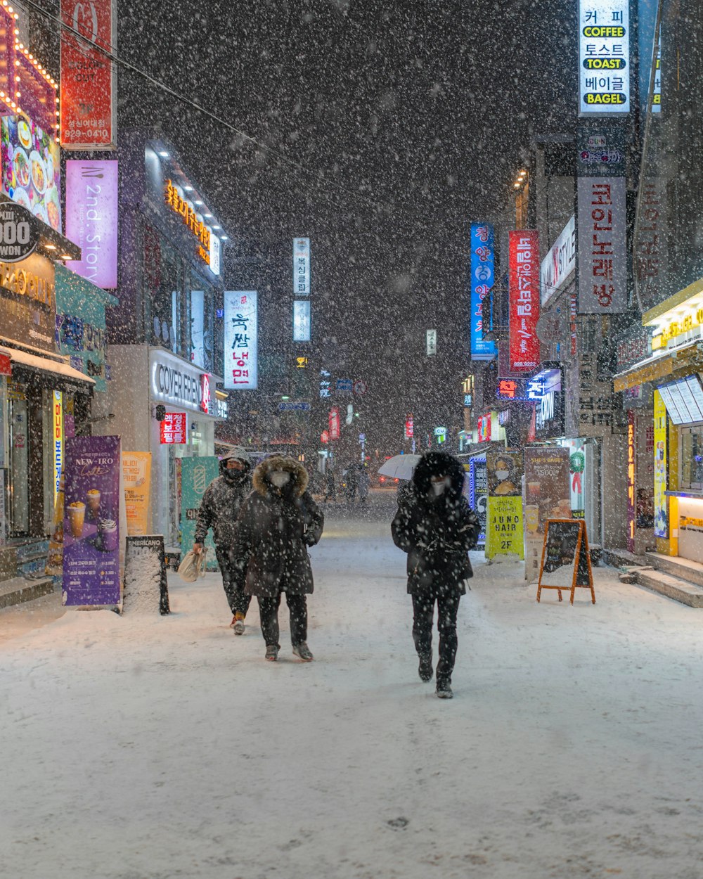 a couple of people walking down a snow covered street