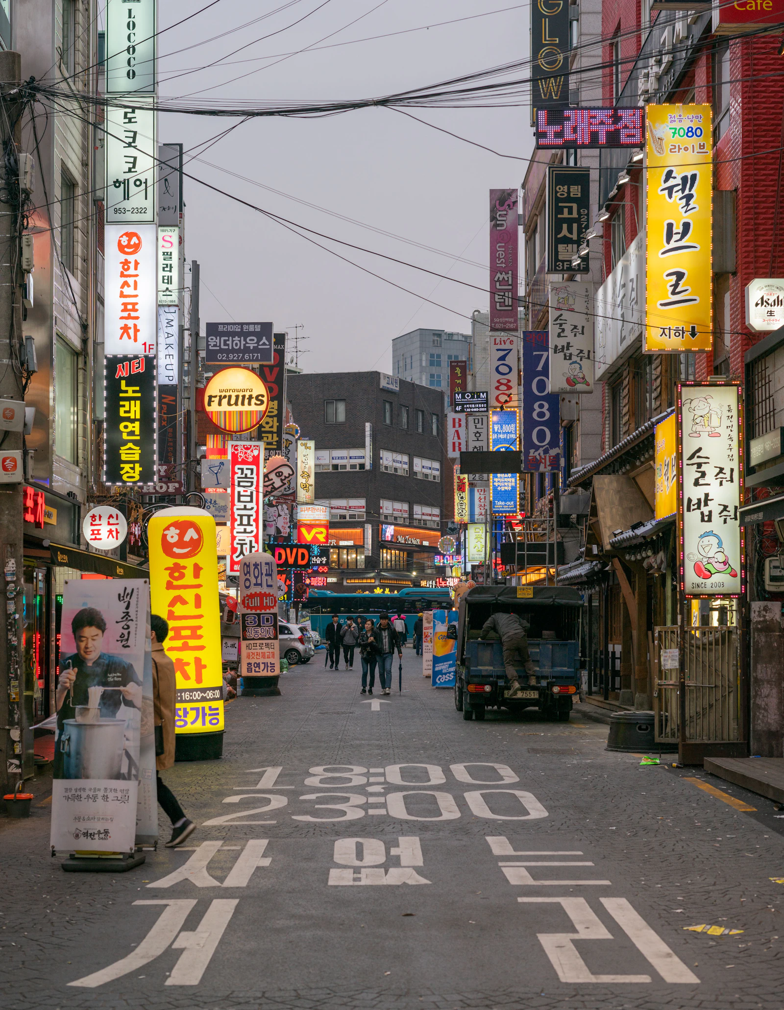 A city street at night lined with lit-up shop signs