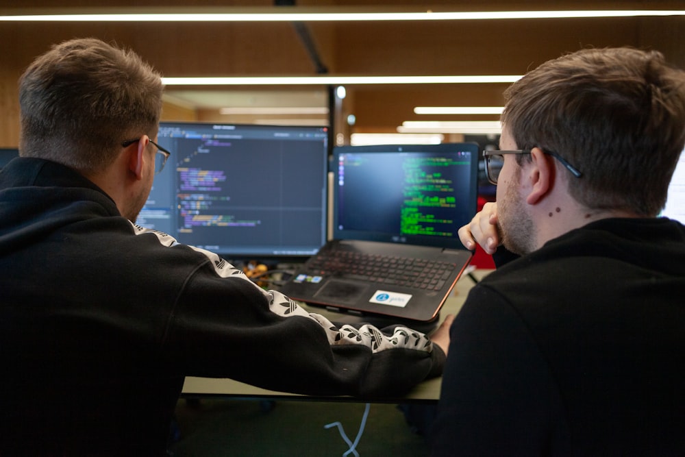 two men sitting in front of a laptop computer