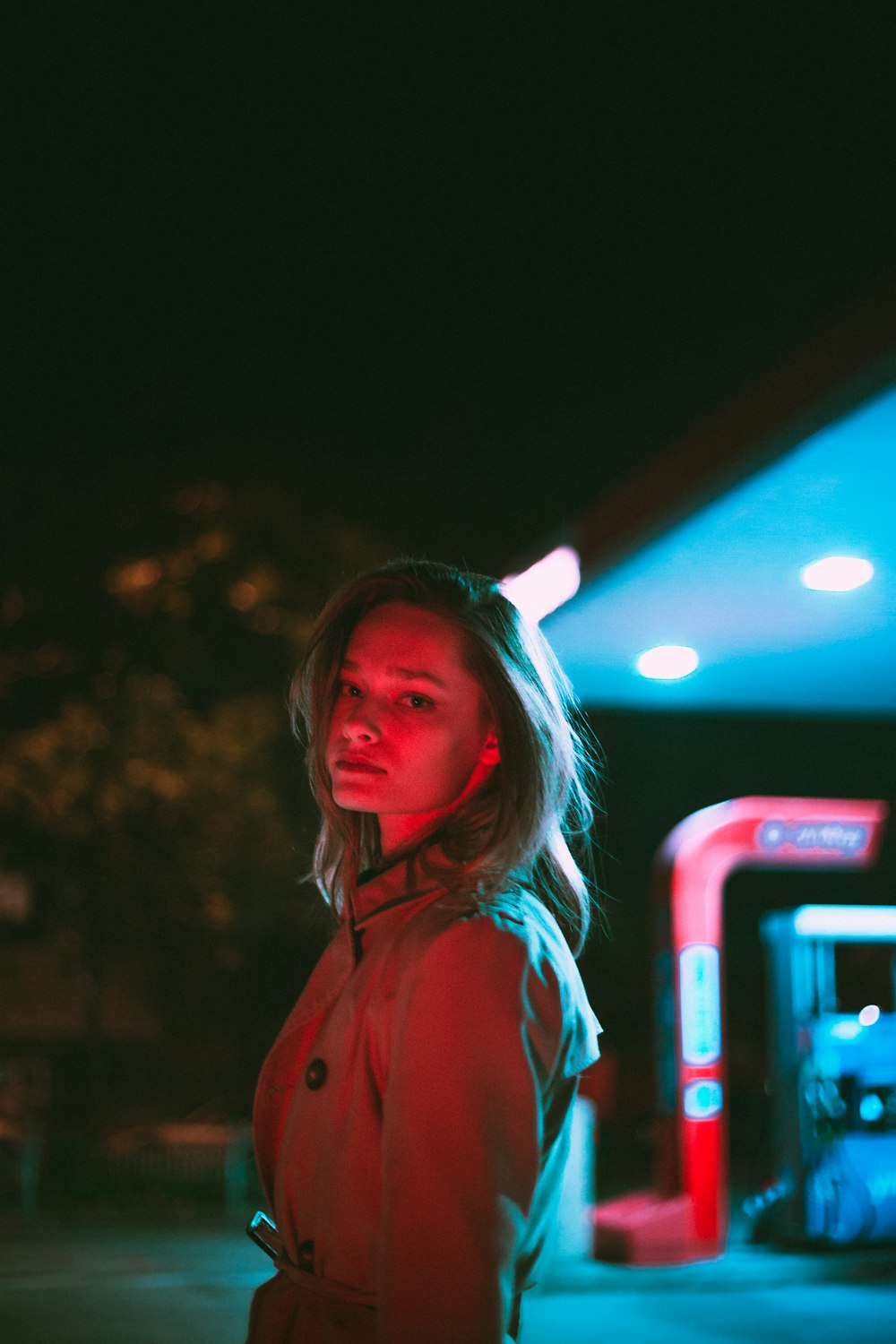 a woman standing in front of a gas station at night