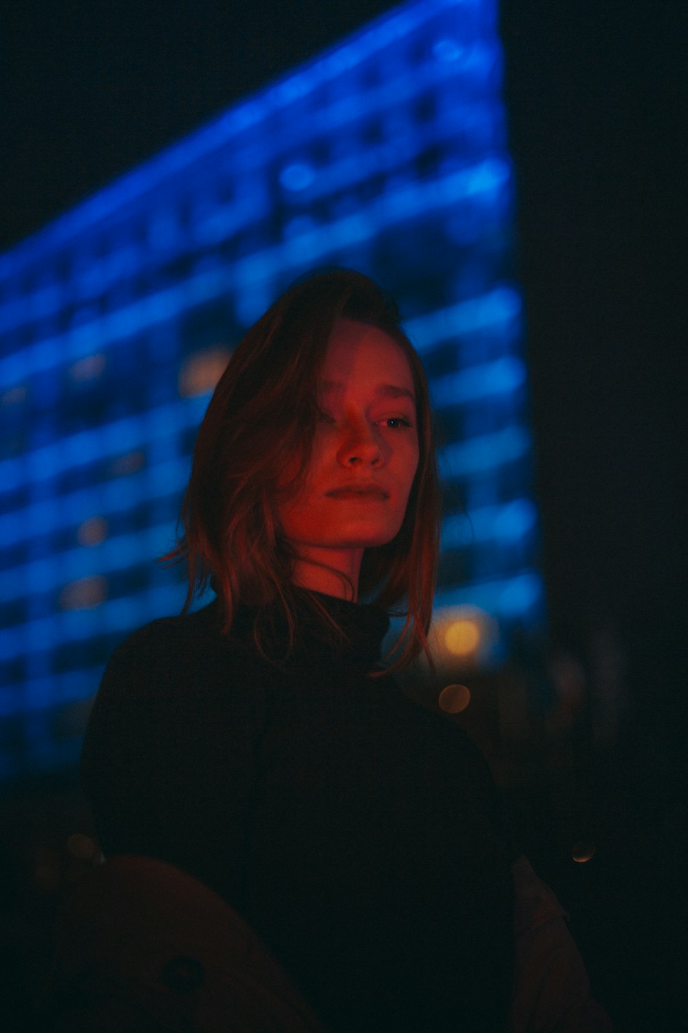 a woman standing in front of a building at night