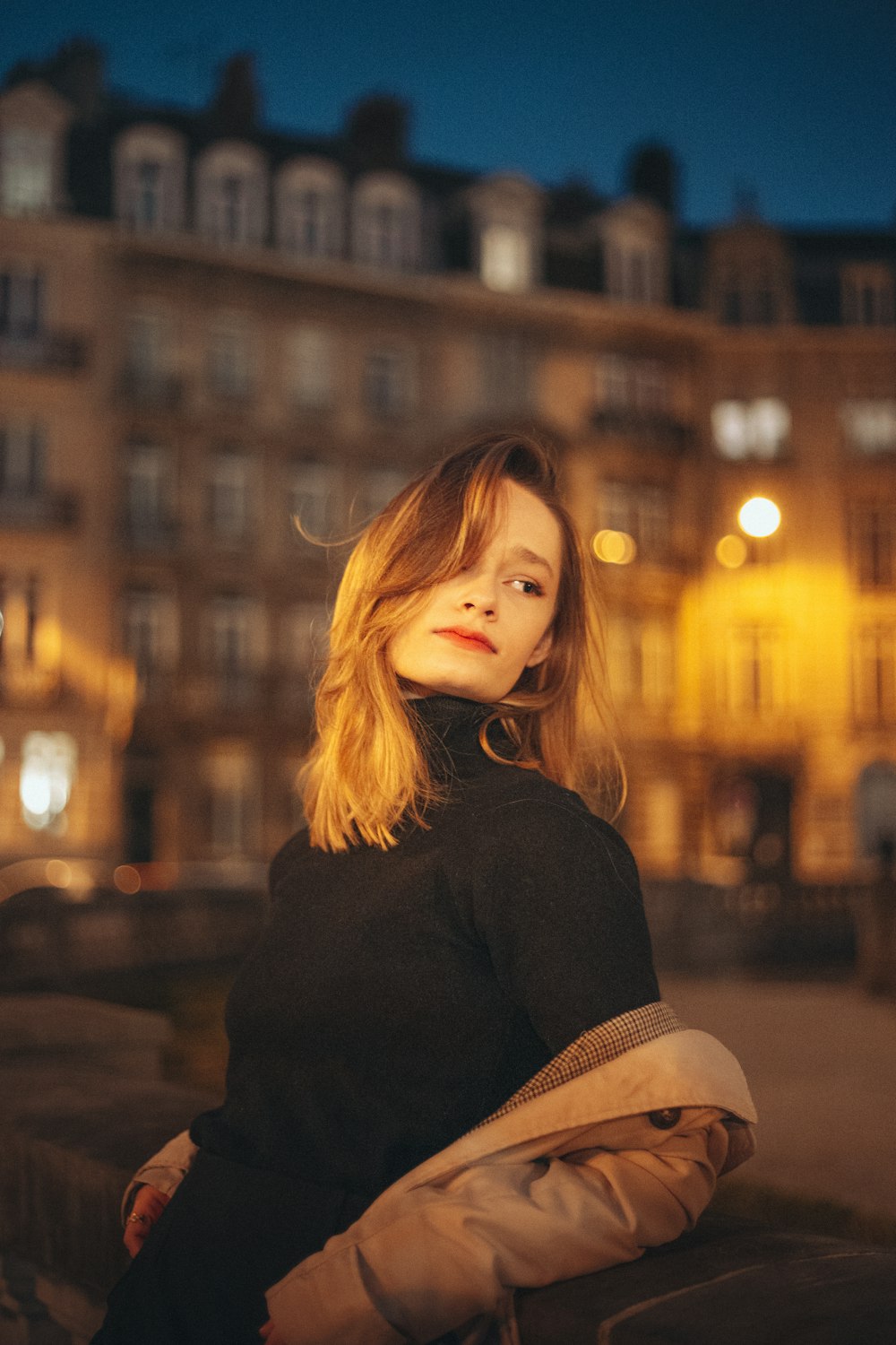 a woman standing in front of a building at night