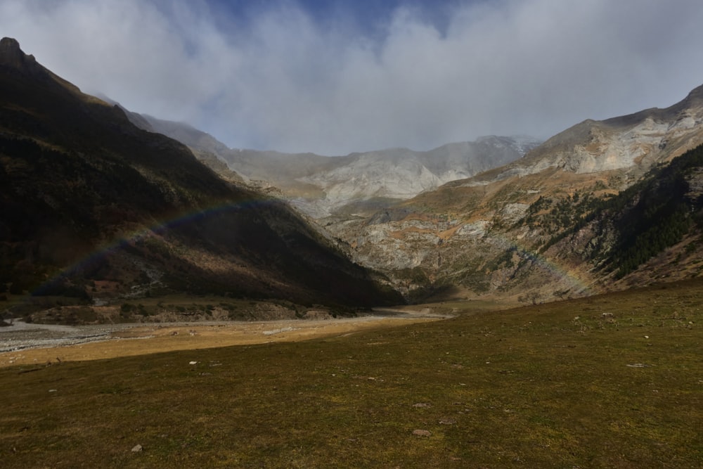 a rainbow shines in the sky over a valley