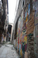 A narrow alleyway framed by old brick buildings with vibrant street art.
