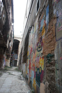 A narrow alleyway framed by old brick buildings with vibrant street art.