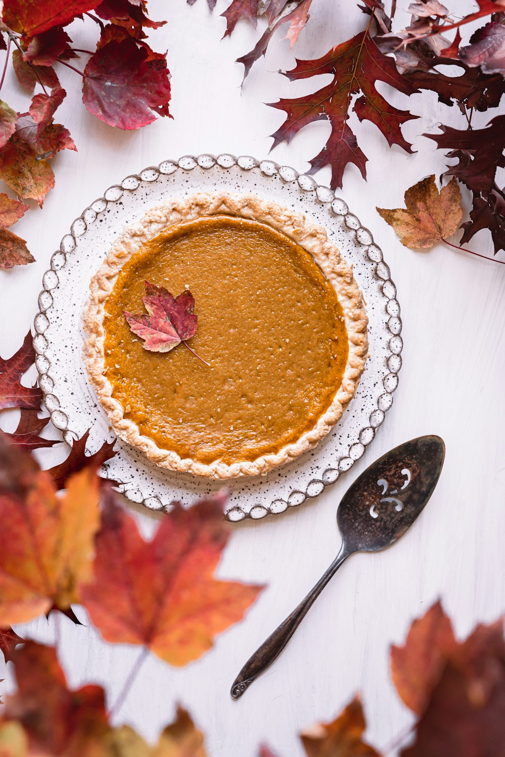 a pie sitting on top of a white table next to leaves