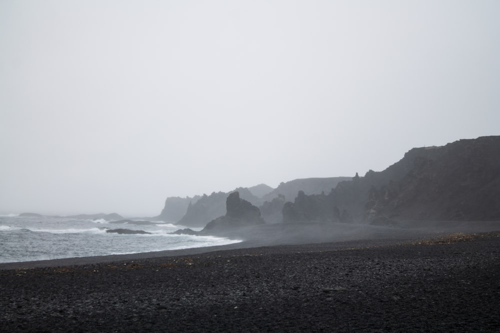 a foggy day at the beach with a black sand beach