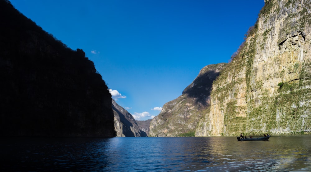 a boat floating on top of a lake next to a mountain