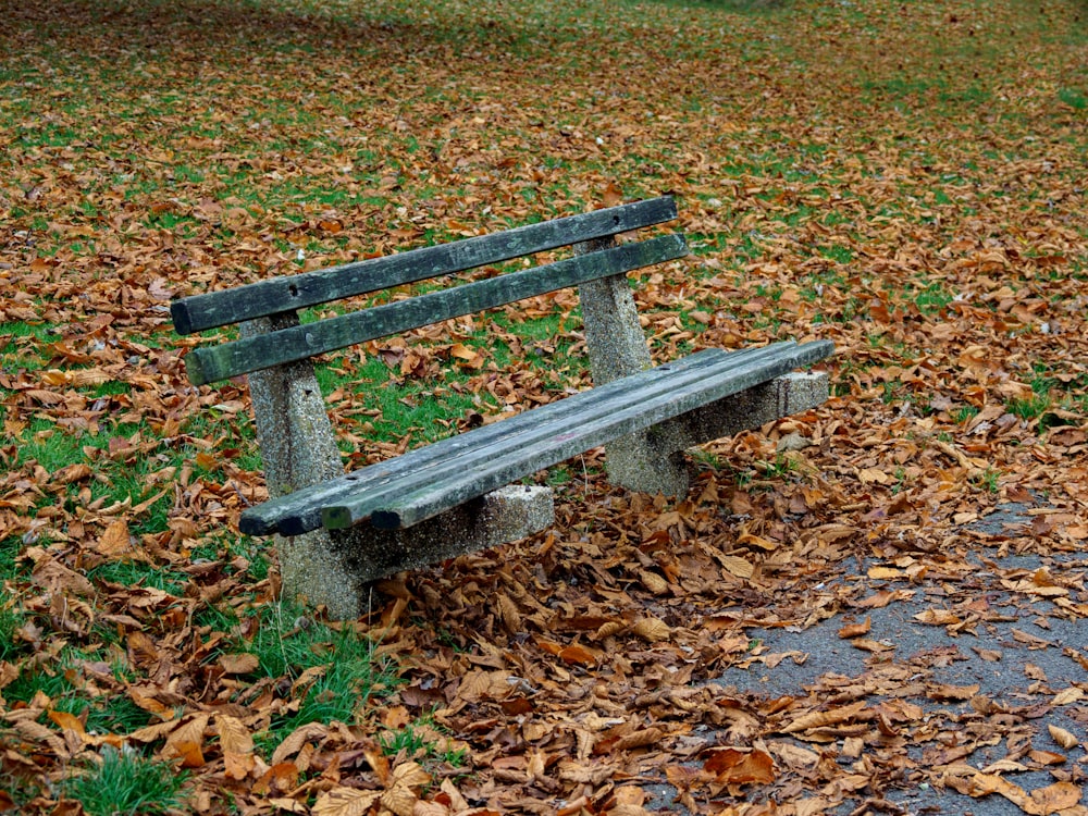 a wooden bench sitting on top of a pile of leaves