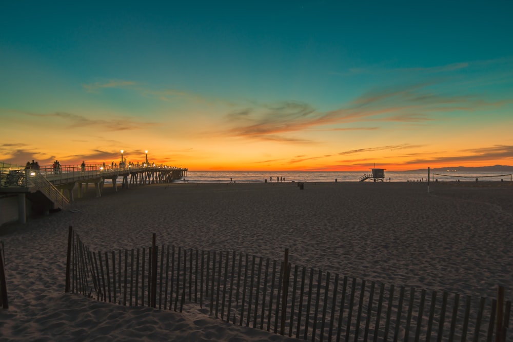 a beach at sunset with a pier in the background