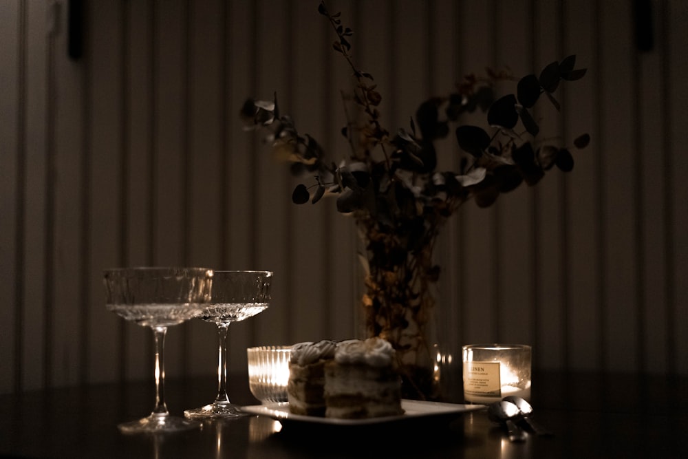 a table topped with a plate of cake next to a vase filled with flowers