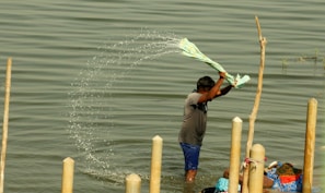 Close-up of hands carefully washing clothes by hand using eco-friendly detergent in a wooden basin.