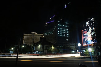 A striking cinematic shot of a sleek marketing campaign billboard glowing against a dark cityscape at night.