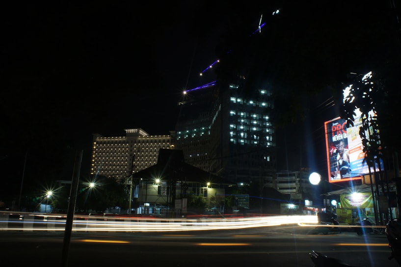 A striking cinematic shot of a sleek marketing campaign billboard glowing against a dark cityscape at night.