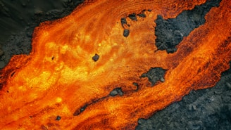 Close-up of molten gold flowing over textured obsidian stone, glowing with raw energy.