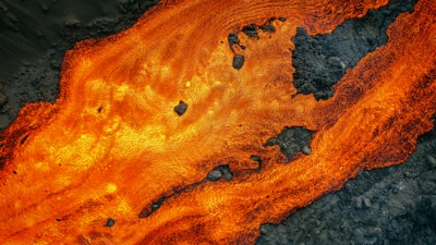 Close-up of molten gold flowing over textured obsidian stone, glowing with raw energy.