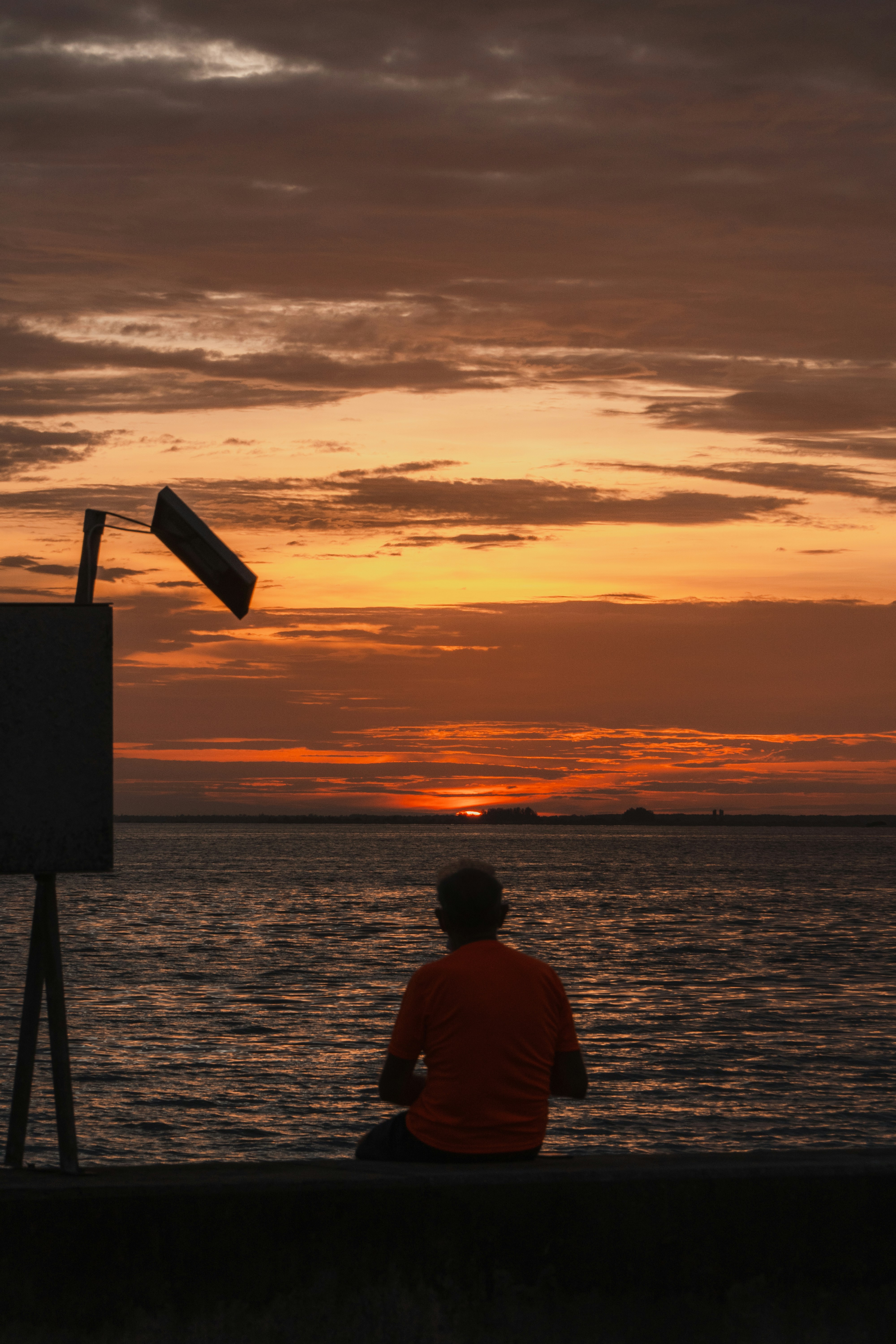 a man sitting on a wall watching the sunset