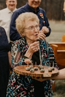 an older woman holding a tray of cupcakes