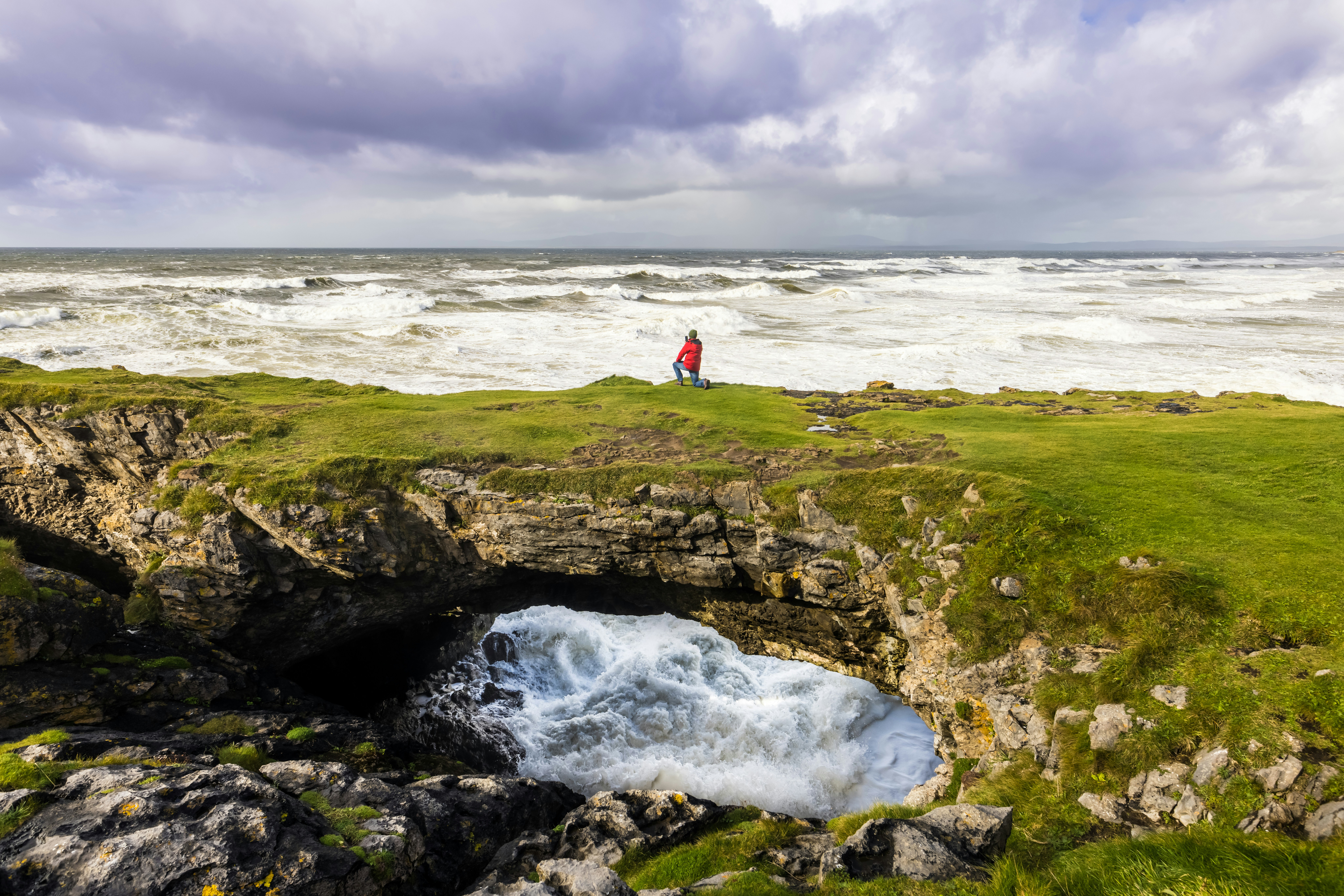 a man standing on top of a cliff next to a body of water
