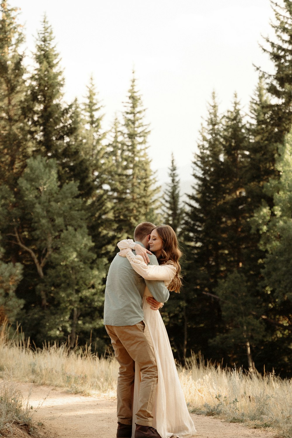 a man and a woman hugging in the middle of a forest