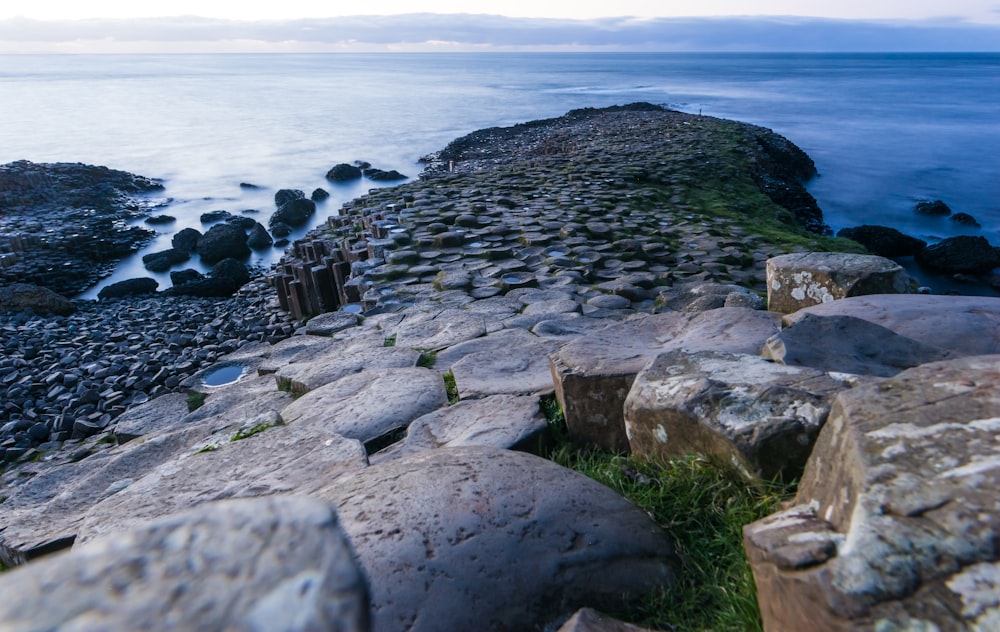 a rocky shore line with a body of water in the background