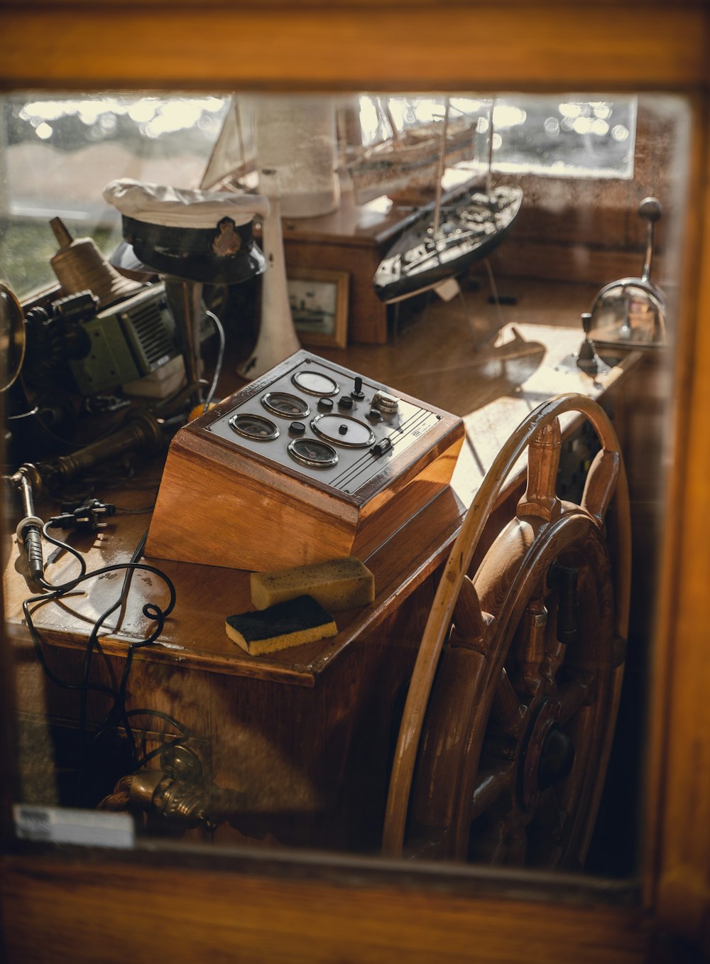 a boat's steering wheel and other items are seen through a window