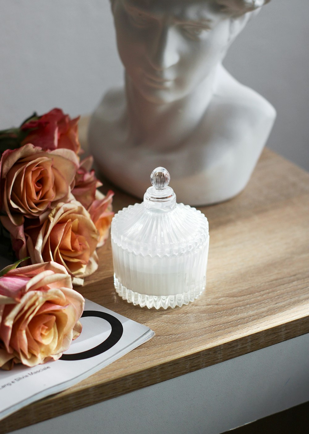 a white vase sitting on top of a wooden table