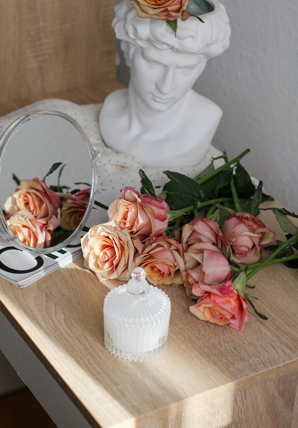 um buquê de rosas sentado em uma mesa ao lado de um espelho