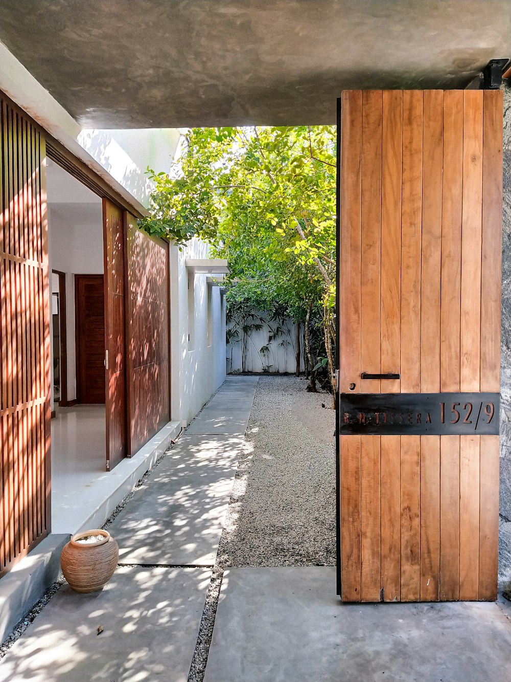 a wooden door is open on a concrete walkway