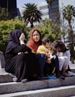 a woman sitting on steps with two children