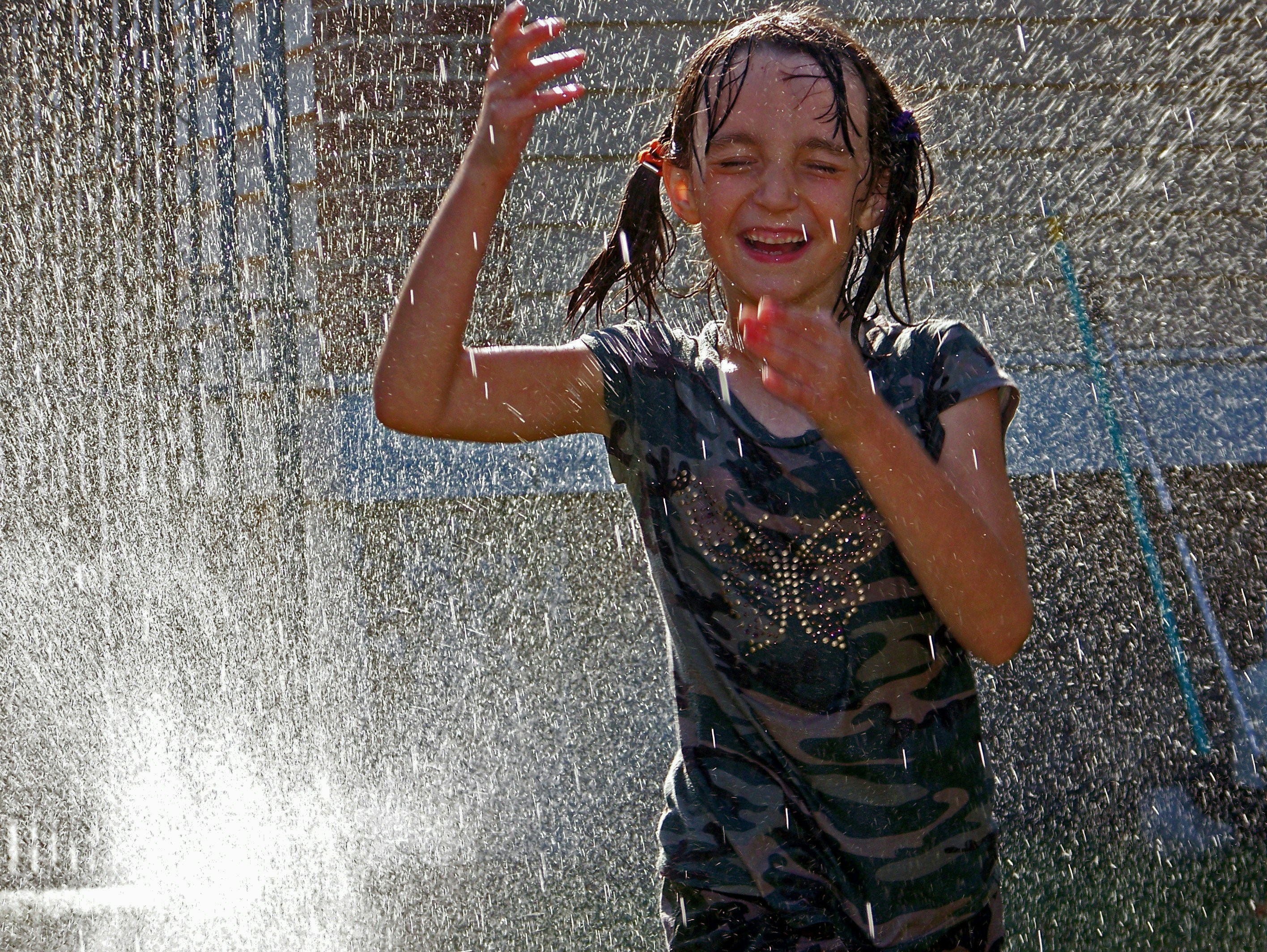 a young girl playing in a sprinkle fountain
