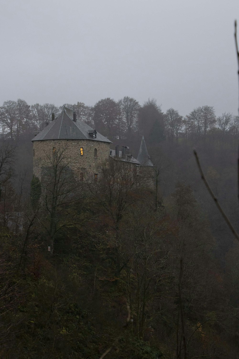 an old building on a hill surrounded by trees