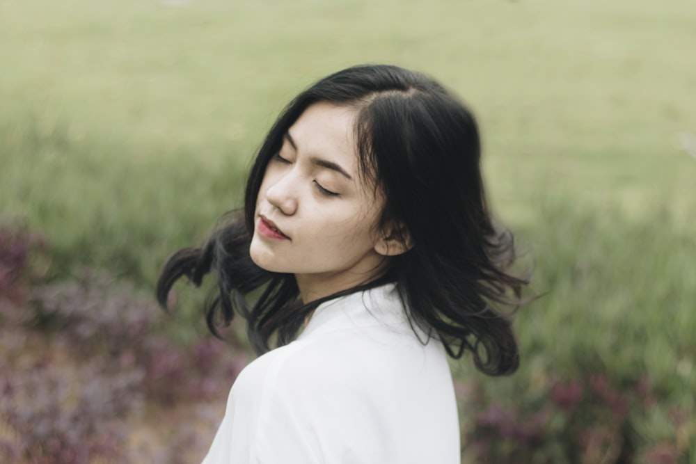 a woman standing in a field with her eyes closed