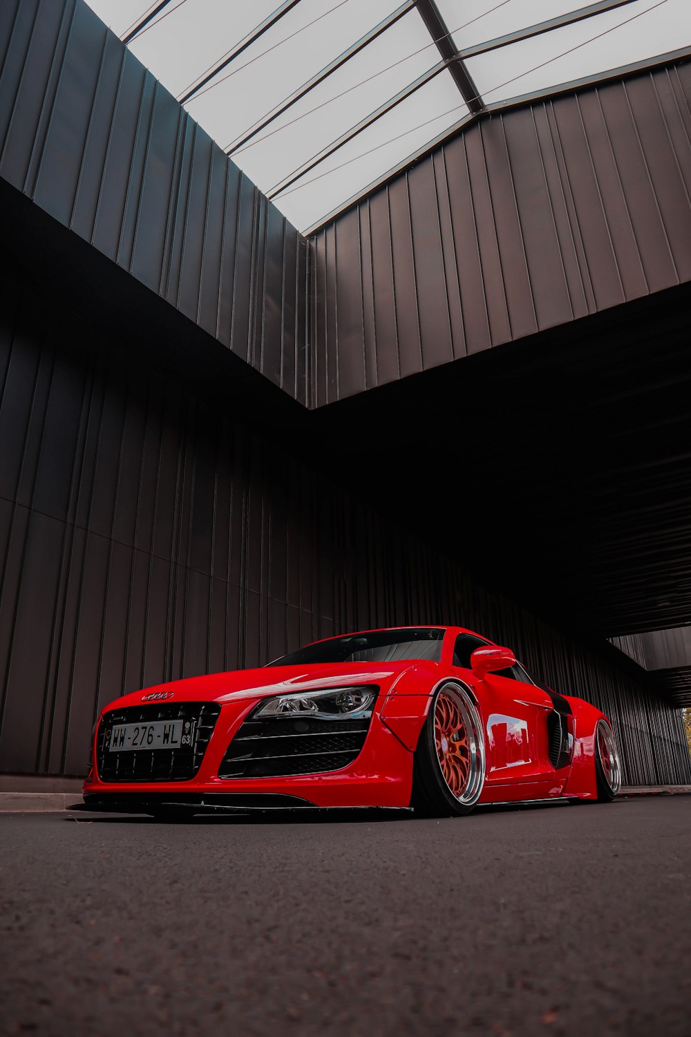 Une voiture de sport rouge garée devant un immeuble