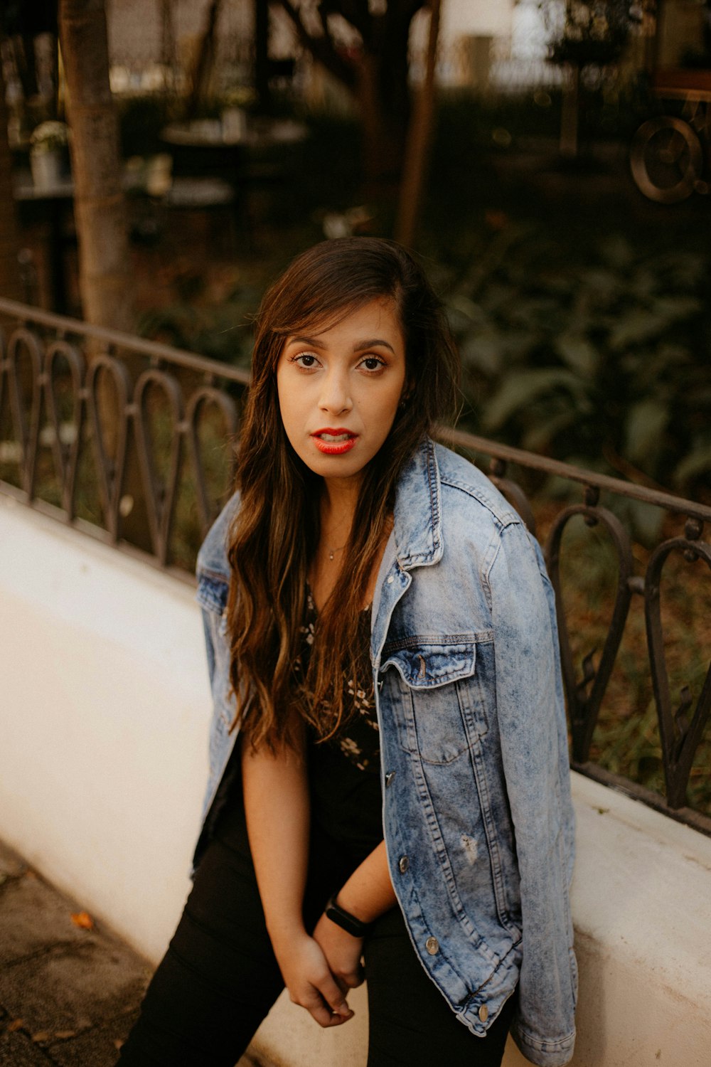 a woman leaning against a wall with a jean jacket on