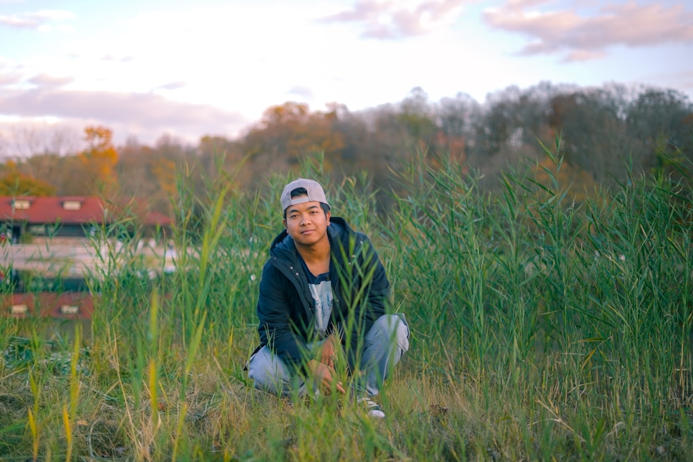 a man kneeling down in a field of tall grass