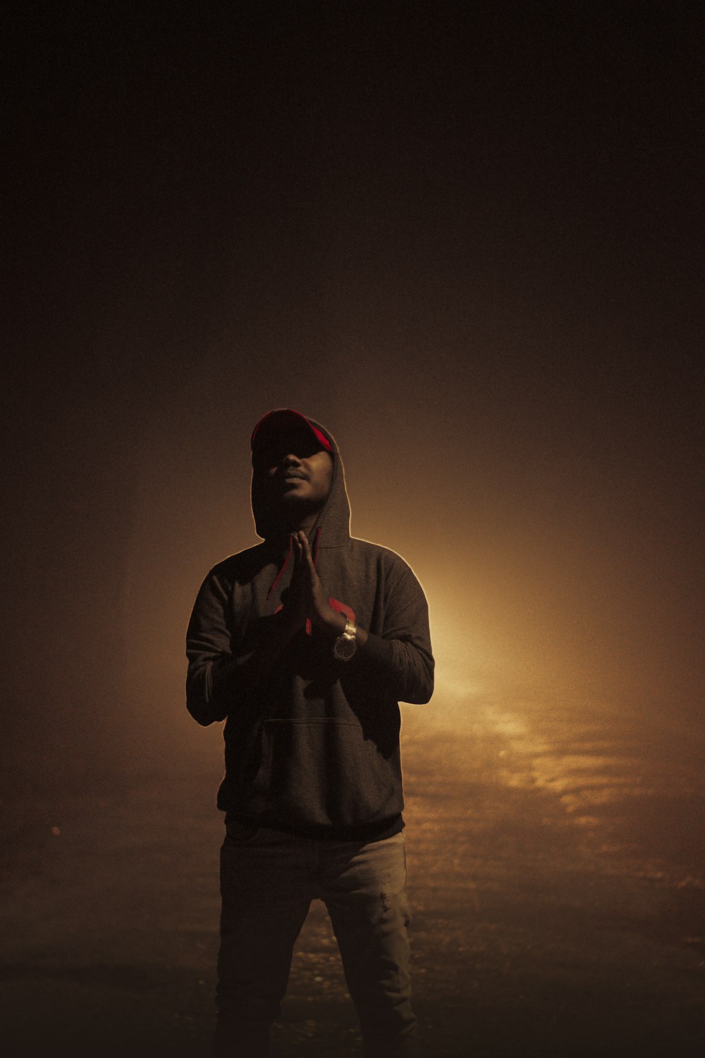 a man in a hoodie standing in the dark