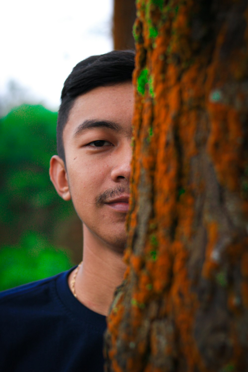 a man standing next to a tree in a forest