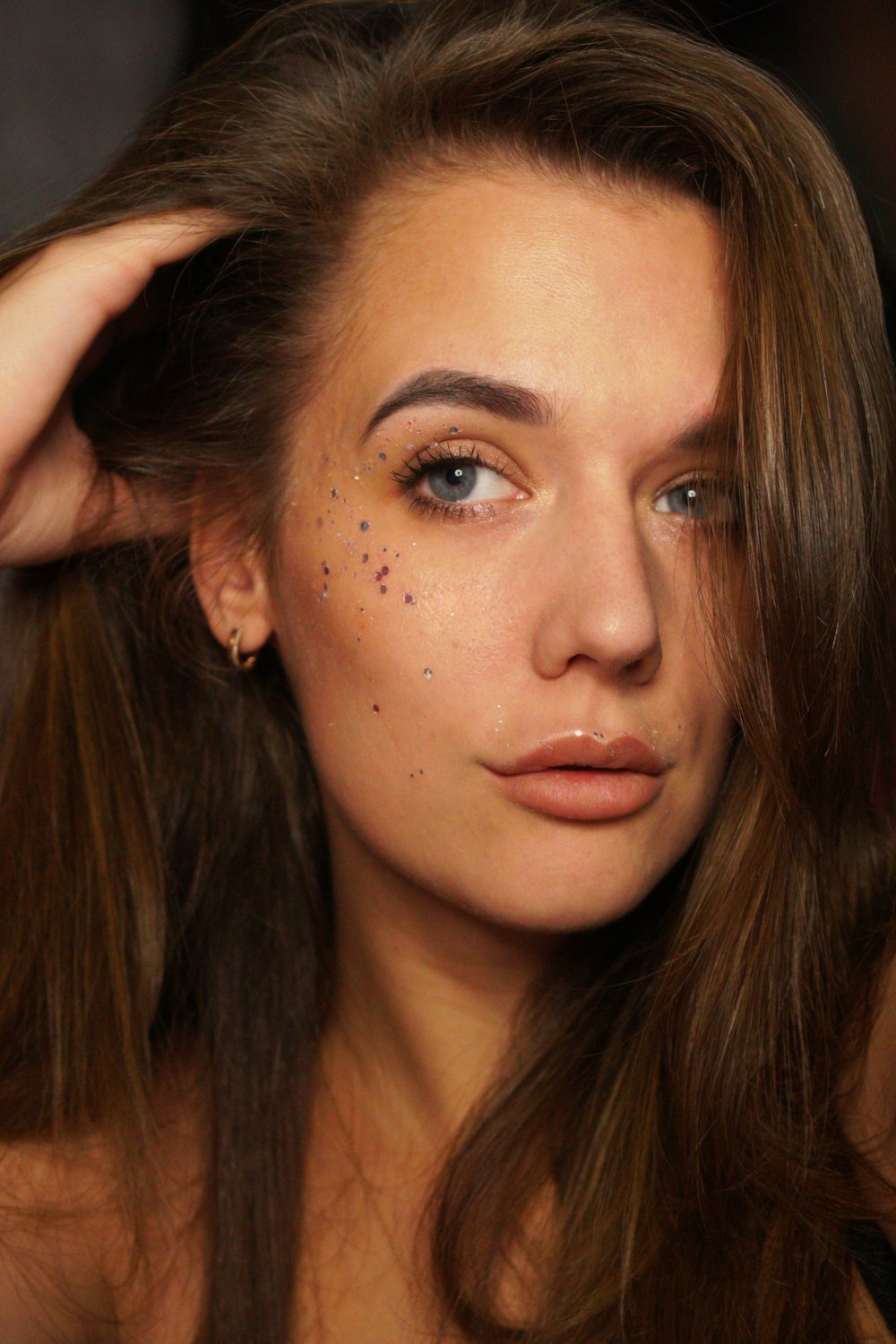 a woman with makeup on her face holding her hair