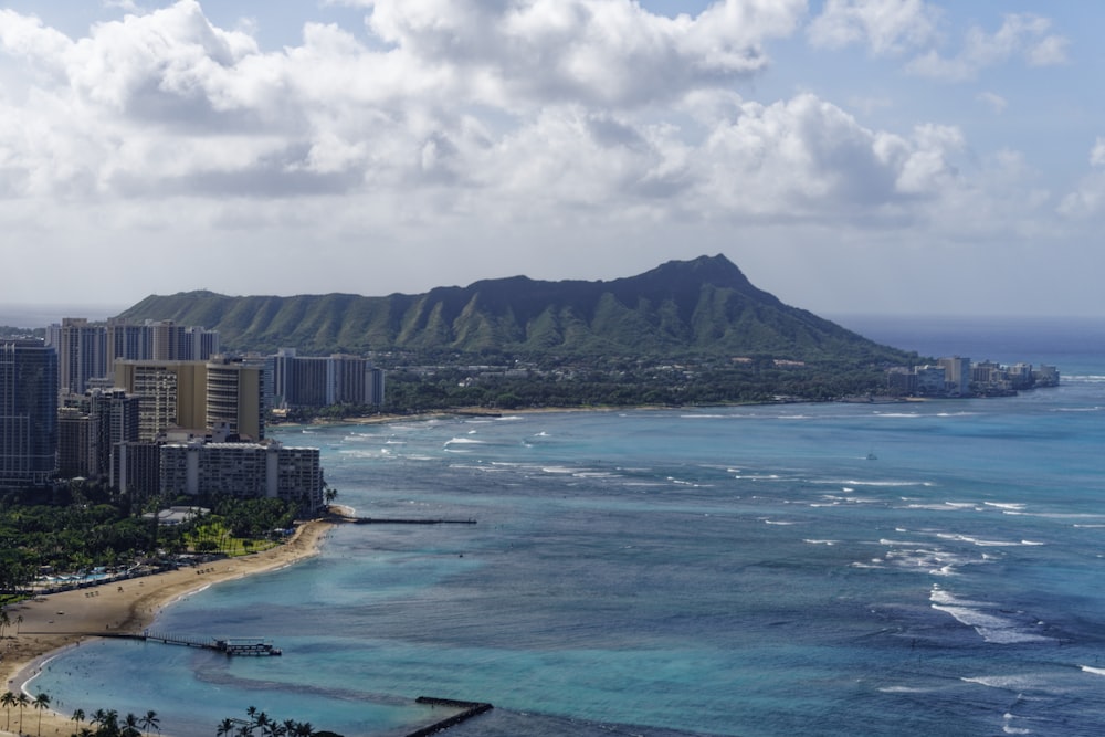 a view of a beach with buildings and mountains in the background