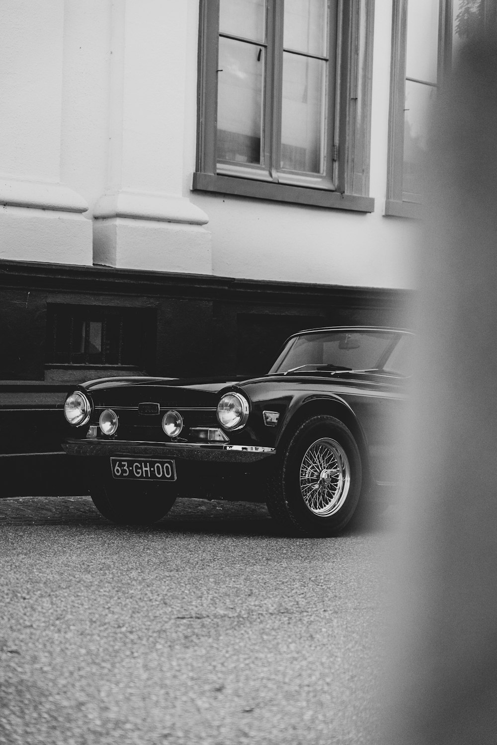 ein Schwarz-Weiß-Foto eines Autos, das vor einem Gebäude geparkt ist