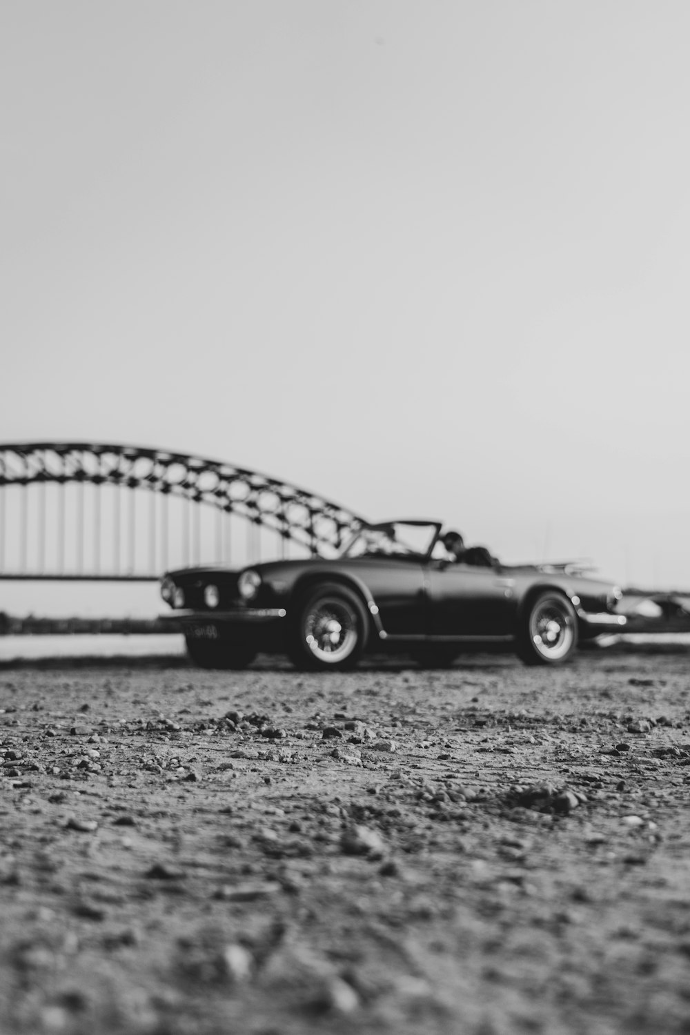 a black and white photo of a car and a bridge
